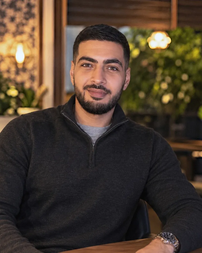 Mohamed Shehab, de maker achter MDY Design, aan een tafel in een warm verlicht café